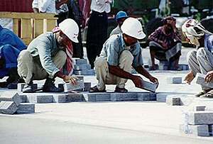Laying pavers by hand is a labour-intensive task.
